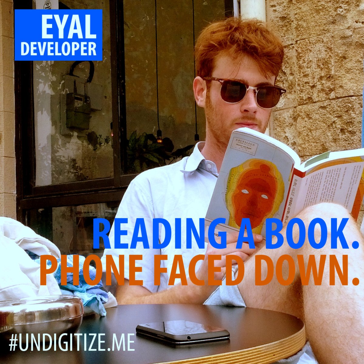 Reading a book. Phone faced down.